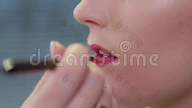 专业化妆师用刷子在客户的嘴唇上涂上唇彩。